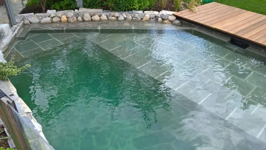 Naturpool mit Steinplatten und Holzdeck